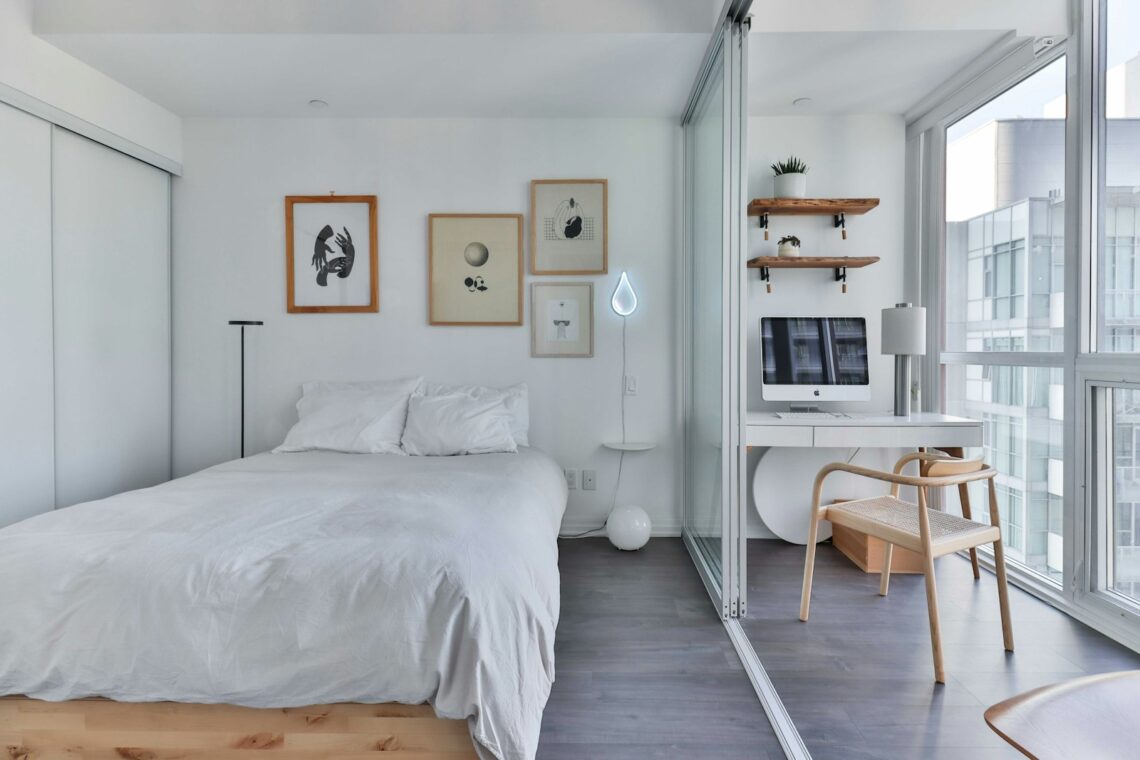minimalist small apartment bedroom with no headboard, gallery art on walls, desk nook