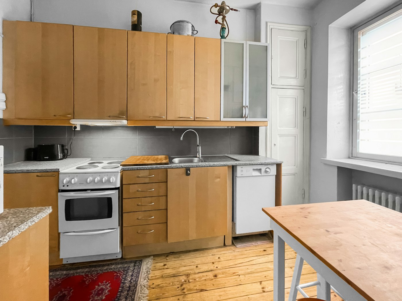 Budget first apartment kitchen with basic stove wood cabinets and a small table for a college graduate