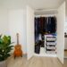 open white apartment wardrobe with hanging clothes and plastic storage drawers