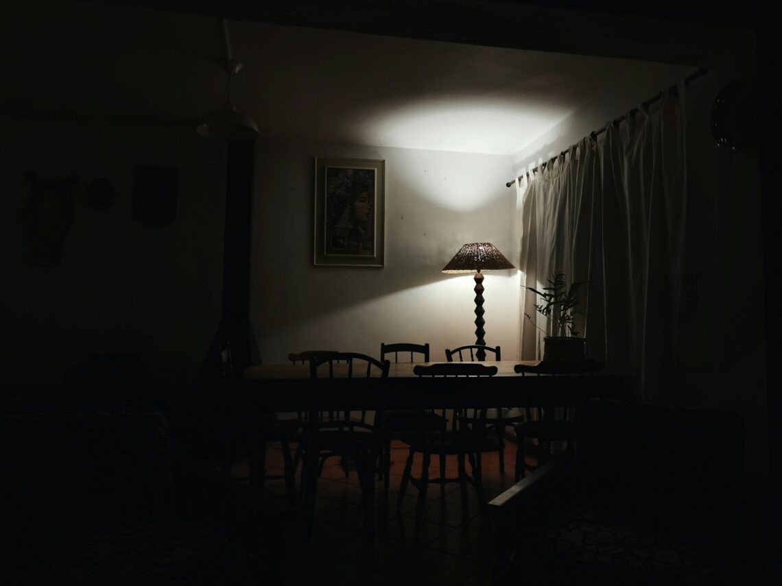 dark dining room in apartment lit only by a single warm floor lamp