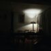 dark dining room in apartment lit only by a single warm floor lamp