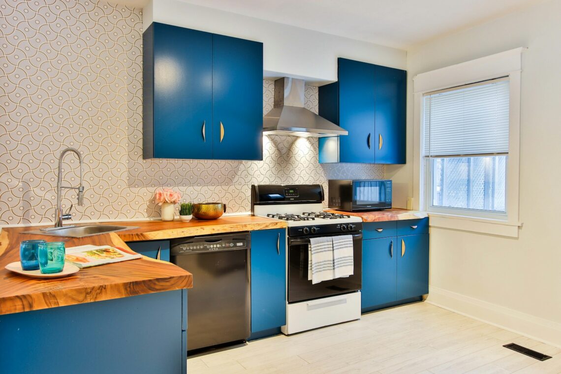small rental kitchen with bold blue cabinets and patterned peel and stick backsplash