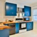 small rental kitchen with bold blue cabinets and patterned peel and stick backsplash