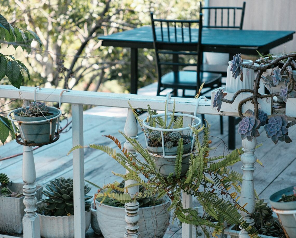 Small balcony railing with succulent planters and a table in the background
