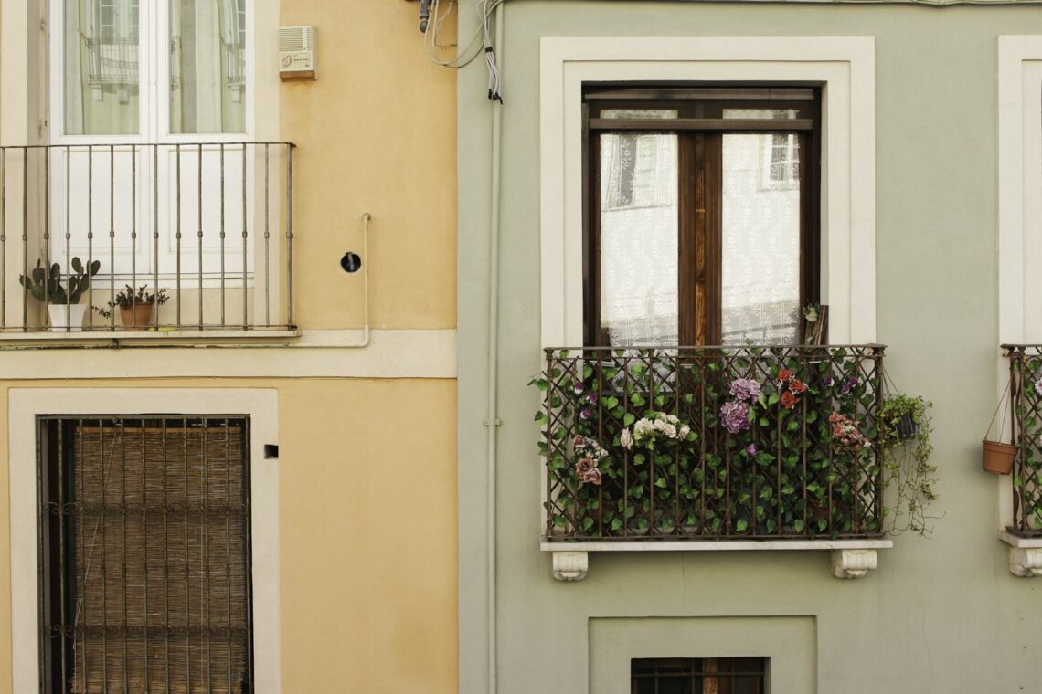 Colorful European apartment building facades with small flower-filled wrought-iron balconies