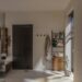 Cozy rental bathroom with robe, ladder shelf, and plant in warm neutral tones