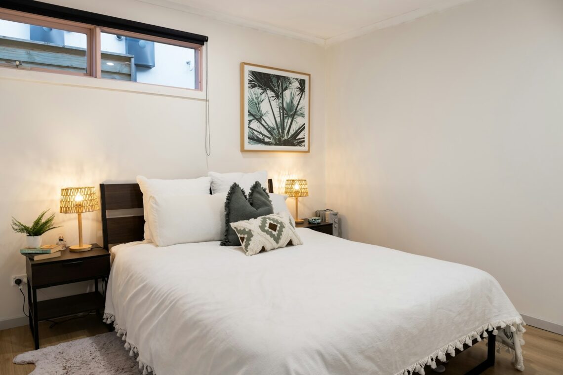 small apartment decor for single woman with white bedding and palm art