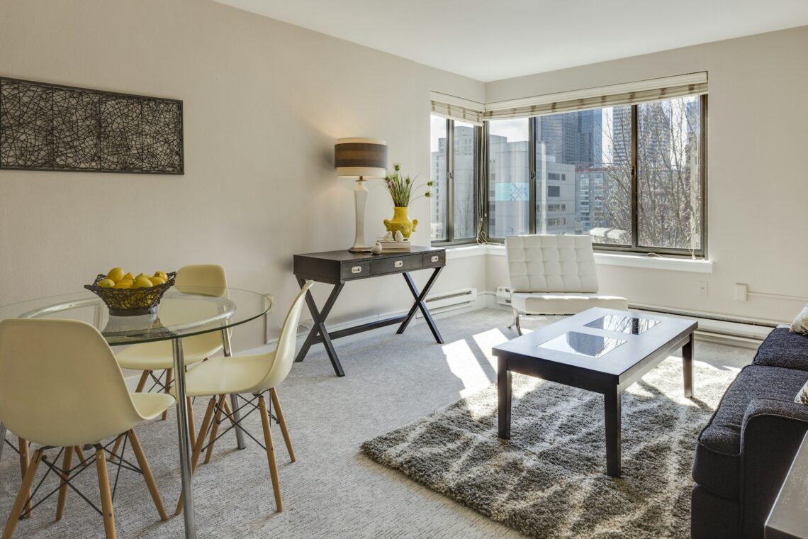 Small apartment living room with round glass dining table and city view