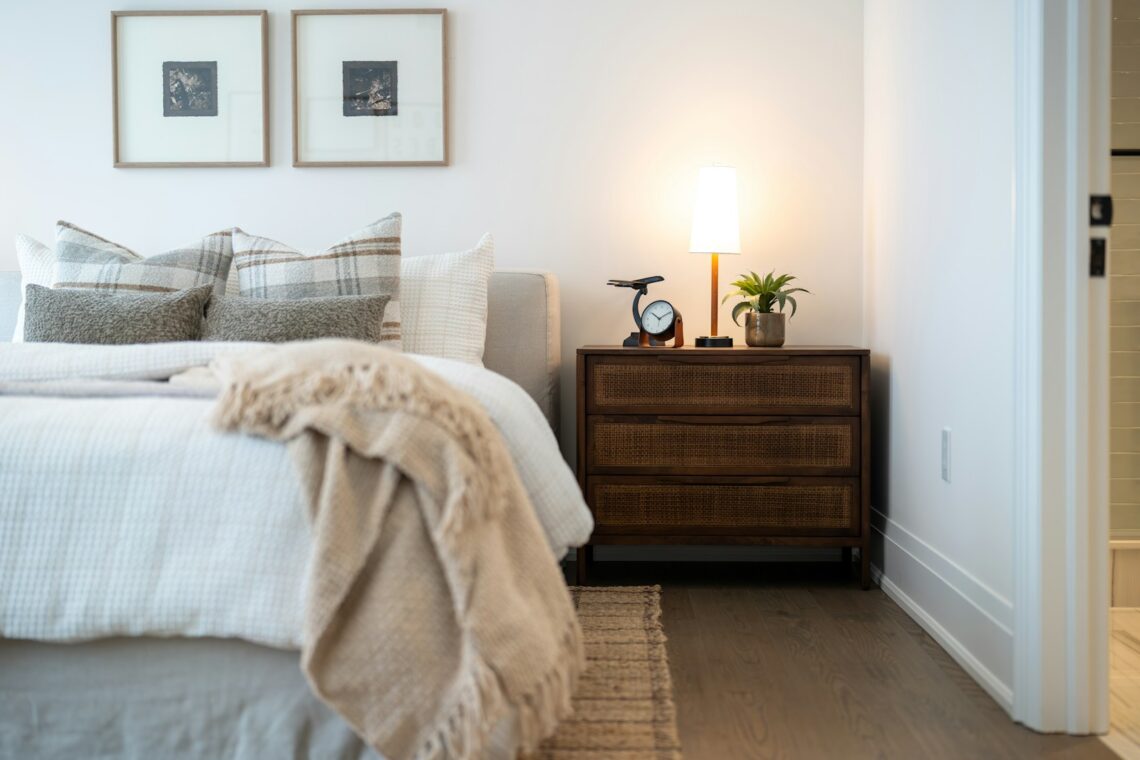 Cozy apartment bedroom with two framed art pieces on the wall and warm bedside lamp on rattan nightstand