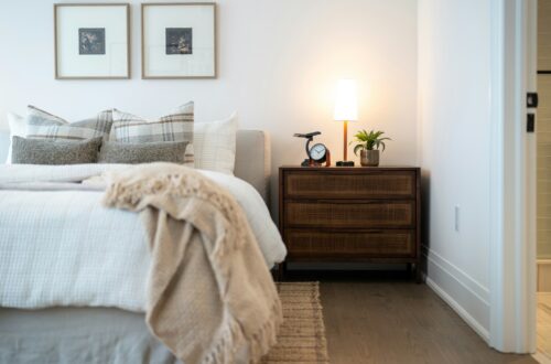 Cozy apartment bedroom with two framed art pieces on the wall and warm bedside lamp on rattan nightstand