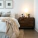 Cozy apartment bedroom with two framed art pieces on the wall and warm bedside lamp on rattan nightstand