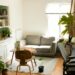 cozy apartment living room filled with potted indoor plants and a hanging planter beside a bookshelf