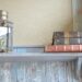 Antique lantern and vintage leather-bound books on a rustic wooden shelf, cottagecore reading nook styling