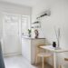 Scandi small apartment kitchen with a compact fold-down table and wooden chairs tucked against the wall