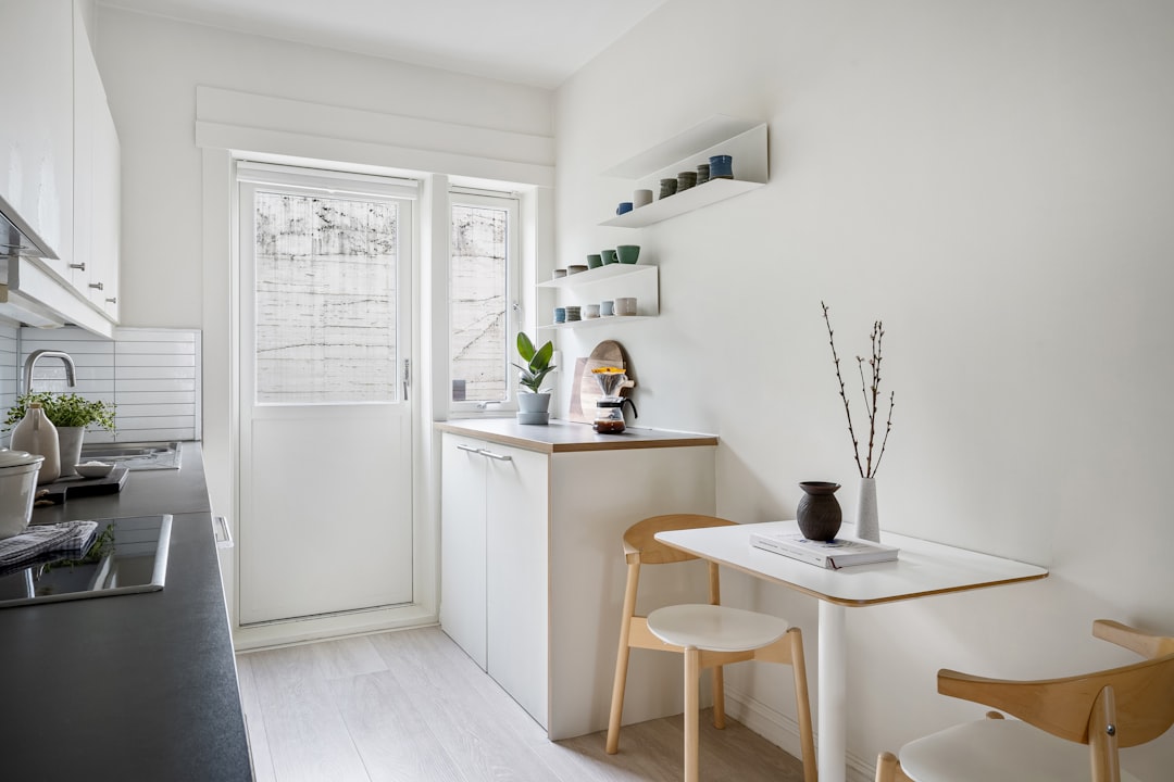 Scandi small apartment kitchen with a compact fold-down table and wooden chairs tucked against the wall