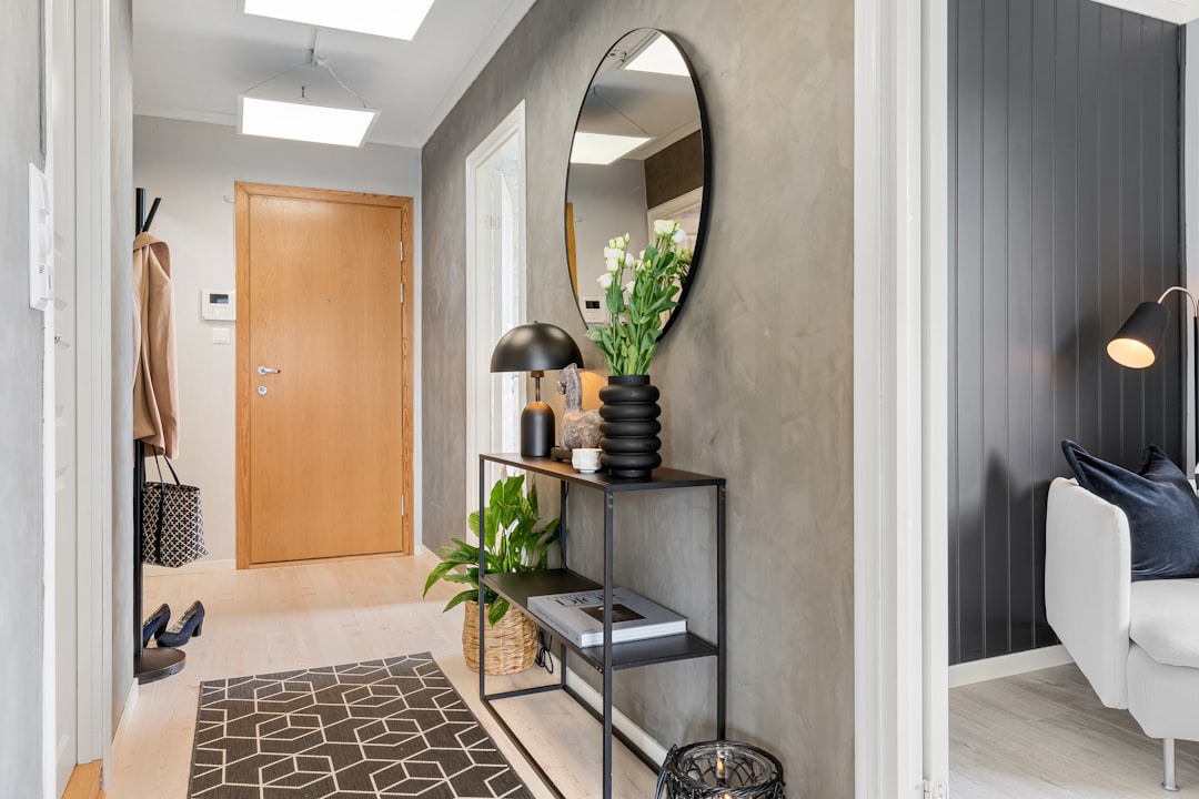 Apartment hallway with slim console table, oval mirror, area rug, and shoes by front door