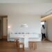 Japandi small apartment dining nook with light oak floor, paper globe pendant, white walls, small round table, and stacked beech wood stools