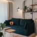Small apartment living room with navy blue sofa, swing-arm lamp, and cane side table in mid-century modern style