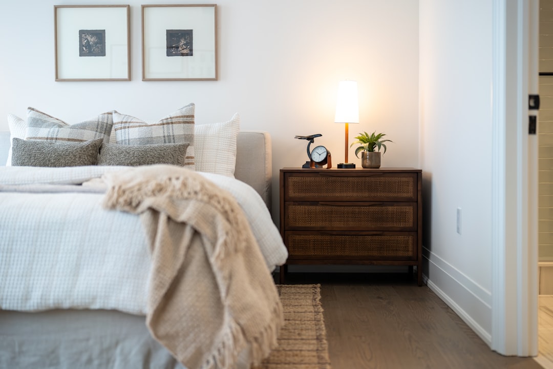 cozy apartment bedroom with cane nightstand drawer and warm table lamp glowing beside the bed