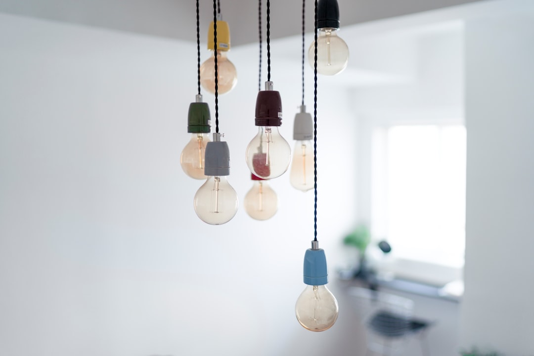 multiple colorful cord pendant lights with globe Edison bulbs hanging in bright white apartment