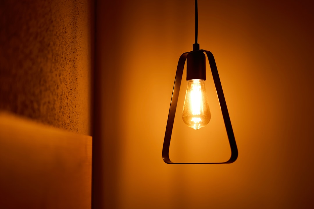 geometric metal frame pendant light with Edison bulb glowing warm orange