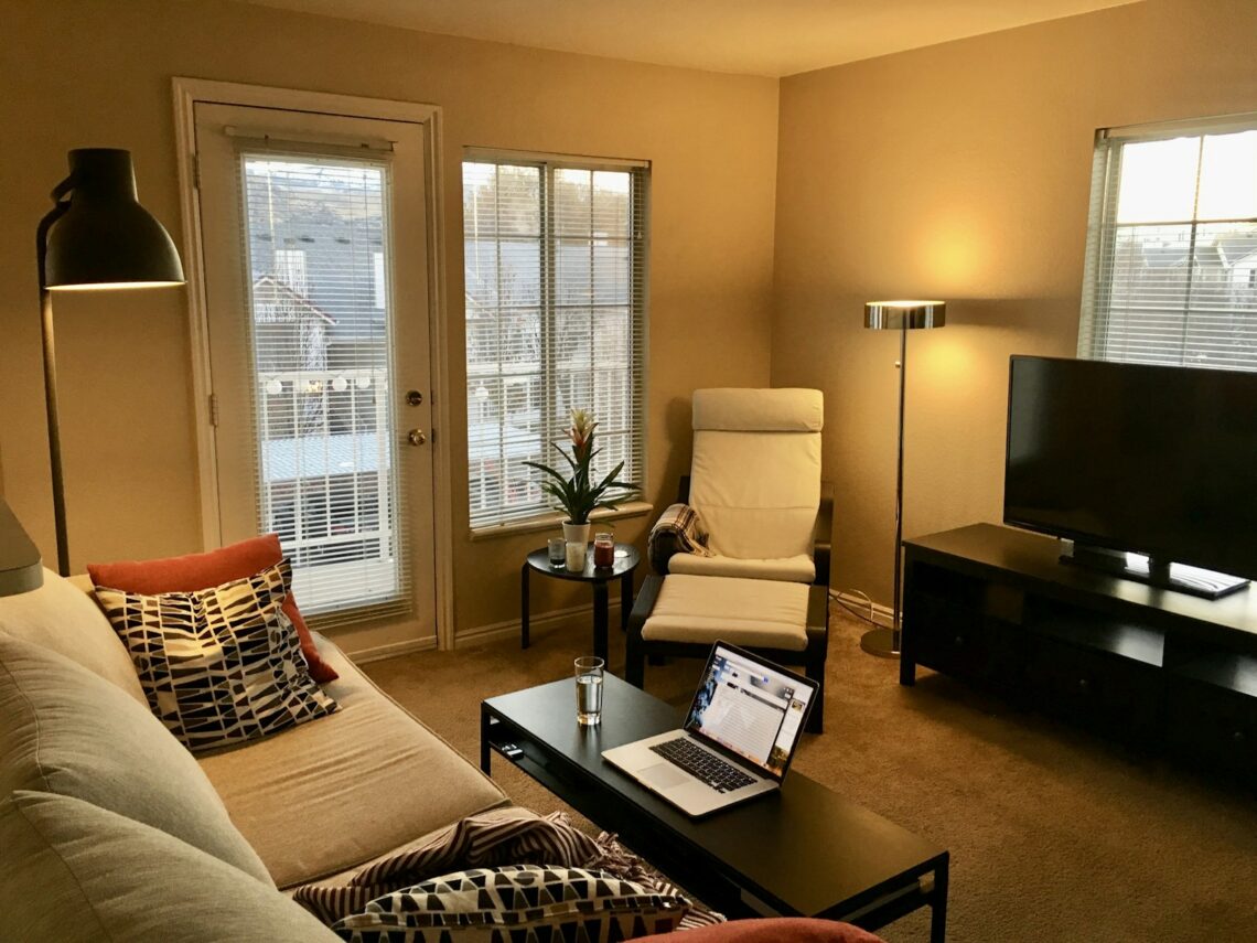 Cozy small apartment living room furnished with IKEA sofa, armchair, coffee table and floor lamp
