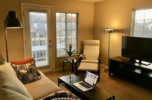 Cozy small apartment living room furnished with IKEA sofa, armchair, coffee table and floor lamp