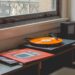 Orange vinyl record spinning on turntable by apartment window with Wilco album cover nearby